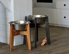 two metal bowls sitting on top of a wooden floor next to a stair case and table