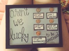 a person holding a framed sign with words and coins on it that says, aren't we lucky?