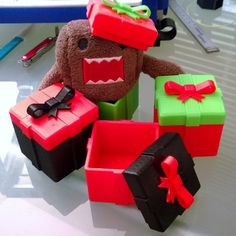 a stuffed animal sitting next to several boxes with presents on it's head and mouth