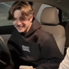 two people sitting in a car and one is smiling