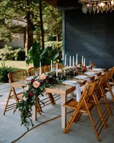 a long table with candles and flowers on it is set up for an outdoor dinner