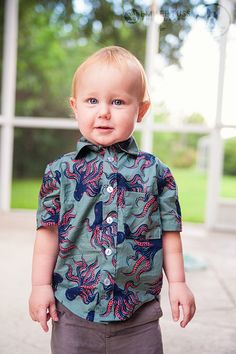 a little boy that is standing up with his hands in his pockets and looking at the camera