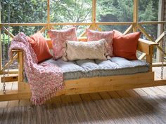 a wooden porch swing with pillows on it