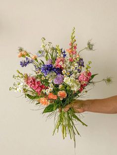 a person is holding a bouquet of flowers in their left hand and the other hand