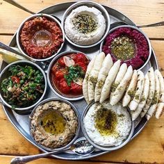 an assortment of different foods on a metal platter with spoons and utensils