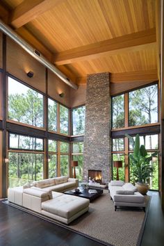 a large living room with high ceilings and floor to ceiling windows that overlook the trees