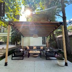 an outdoor living area with couches and tables under a wooden pergoline roof