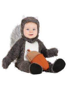 a baby in a squirrel costume sitting on the ground