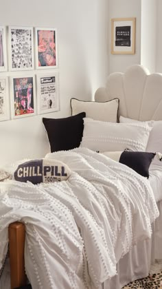 a bed with white sheets and pillows in a bedroom next to pictures on the wall