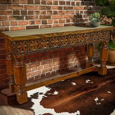 a wooden bench sitting on top of a cowhide rug next to a brick wall