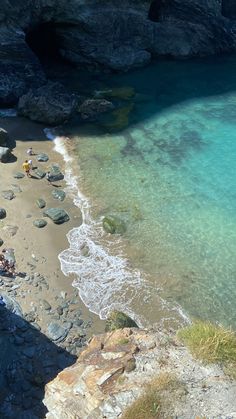 people are sitting at the edge of an ocean cliff and looking out into the water