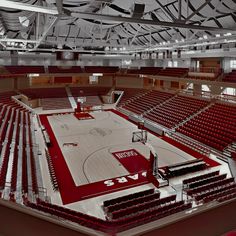 an empty basketball court with red seats