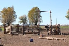 a wooden fence in the middle of an open field with trees and other things around it