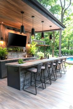 an outdoor kitchen with bar seating and television