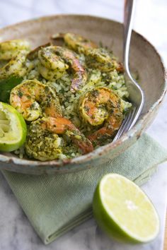 a bowl filled with shrimp and rice next to a lime wedge on a cloth napkin