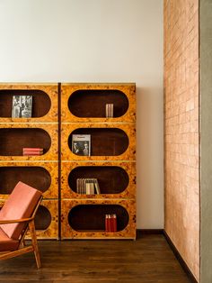 a chair sitting in front of a wooden book shelf with books on it's sides