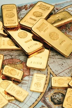 many gold bars are scattered on top of a world map and there is no image here to provide a caption for