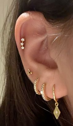 a close up of a person wearing gold ear piercings with diamond shapes on them