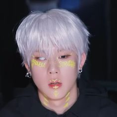 a person with white hair and yellow paint on their face