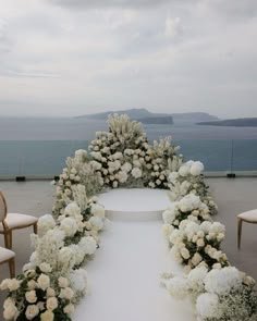 an outdoor ceremony setup with white flowers and greenery on the aisle, overlooking the ocean