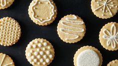 twelve decorated cookies arranged on a black surface