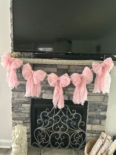 a fireplace decorated with pink tissue pom poms and a flat screen tv above it