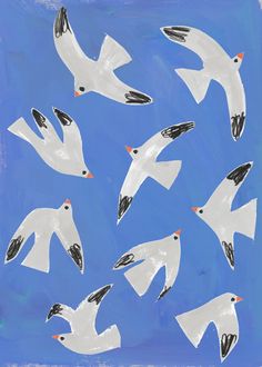 a group of white birds flying through a blue sky