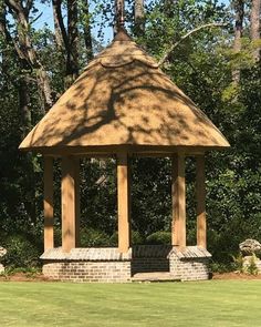 a gazebo sitting in the middle of a lush green field next to some trees