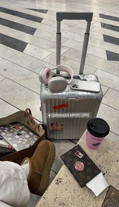 luggage sitting on the ground in front of a person's feet and handbag