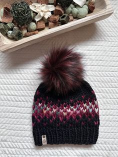 a knitted hat with a pom - pom sitting on top of it