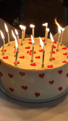 a white cake with red hearts on it and candles in the shape of heart's