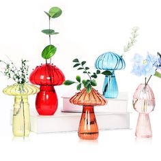 four different colored vases sitting on top of a white book next to each other