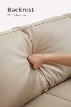 a person is holding the backrest of a couch with their hand on it's pillow