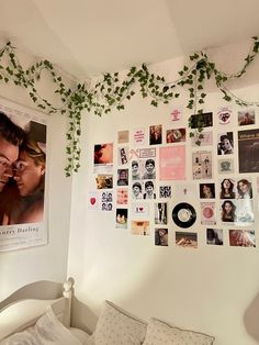 a bedroom with white walls covered in pictures and ivy growing on the wall above the bed