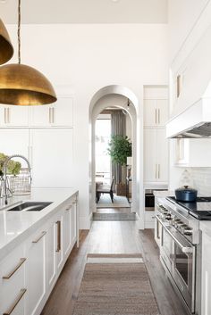 a kitchen with white cabinets and gold accents