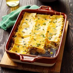 a casserole dish with meat and cheese in it on a wooden cutting board