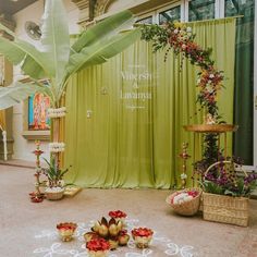 an indoor ceremony with flowers and candles on the floor in front of a green curtain