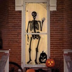 a window decorated for halloween with skeletons and pumpkins