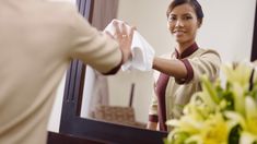 a woman is cleaning her hands in front of a mirror with flowers on the table