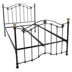 a black metal bed frame with two golden knobs on each side and an arched headboard