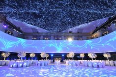 an indoor dance floor is lit up with blue lights and snowflakes on the ceiling