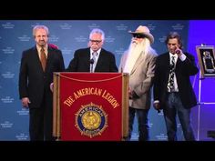 three men in suits and ties are standing behind a podium with an american legend sign on it