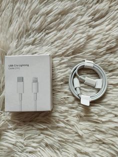 an apple charger and cable sitting on top of a white carpet next to a box