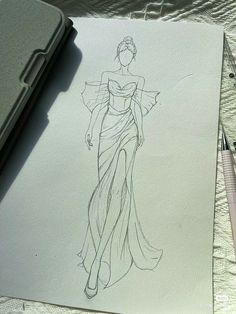 a drawing of a woman's dress on paper next to a pen and marker