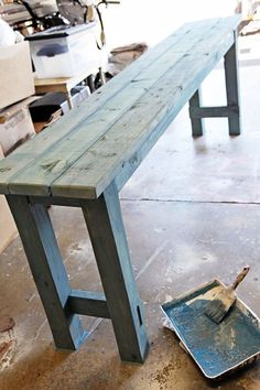 a wooden bench sitting on top of a floor next to a metal pan and brush