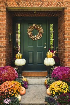 the front door is decorated with pumpkins and flowers