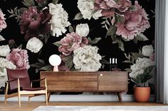 a living room with flowers on the wall and a chair in front of it next to a dresser