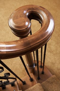 a wooden stair railing with metal handrails on top of carpeted flooring