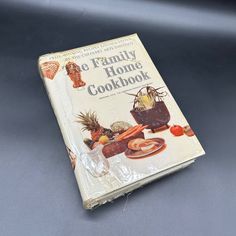 the family home cookbook is sitting on top of a gray tablecloth covered surface