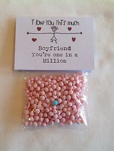 a bag of pink beads sitting on top of a white table next to a card